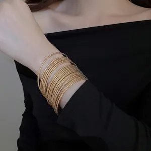 Set of 20 stackable gold metal bangles with intricate textured wave patterns for women