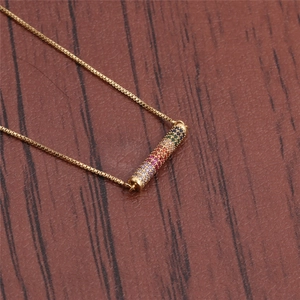 Detailed close-up of golden necklace pendant featuring multi-colored micro-inlaid stones
