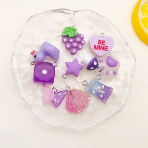 Macro view of purple resin charms like cat paws and hearts in a glass tray