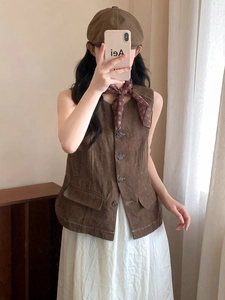 Detail of vintage brown cotton-linen vest paired with floral scarf and white skirt