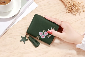 Detail of dark green small zipper wallet with floral embroidery and star tassel charm
