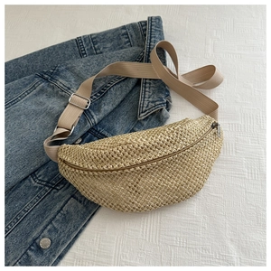 Détail de sac banane en paille tressée avec bandoulière réglable sur fond de veste en jean