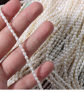 Close-up of 4mm high luster white freshwater rice pearls held by hand to show fine texture