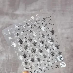 Dettaglio di adesivi per unghie sottili con motivi floreali e pizzo bianco e nero