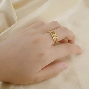 Elegant 18K gold plated titanium steel ring with hollow D-link design on champagne satin