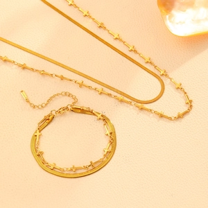Vue détaillée à plat d'un ensemble collier et bracelet doré à double épaisseur sur beige