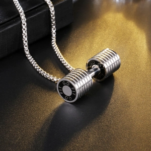 Macro shot of silver stainless steel dumbbell pendant with GO FIT engraving on a textured surface
