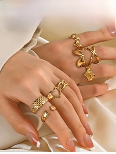 Close-up of gold plated stainless steel heart and butterfly ring set on silk fabric