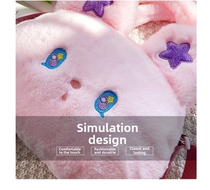 Detail view of plush pink kids bag featuring blue embroidered eyes and star decor
