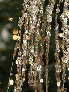 Macro shot of 60cm sparkling golden sequin fringe with a festive bokeh background