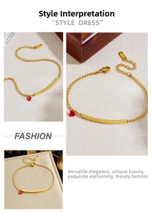 Detail of a gold plated stainless steel bead bracelet with a red heart crystal charm