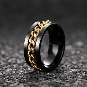 Detail of industrial style black brushed ring featuring a gold cuban chain inlay