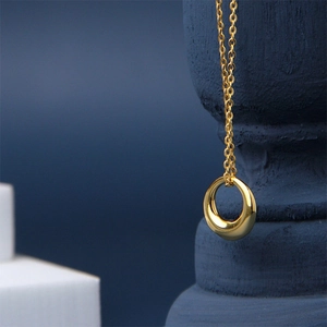 Collier minimaliste plaqué or 18 carats avec pendentif rond sur élégant présentoir bleu