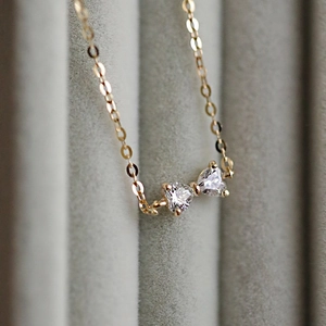 Macro detail of S925 silver bow bracelet featuring two heart-shaped cubic zirconia stones