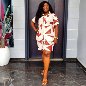 Detailed view of two-piece cream outfit with red geometric prints on shirt and shorts