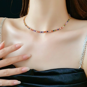 Close-up of a gold-plated necklace with colorful round zircons worn on the neck