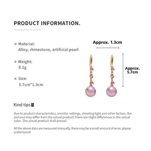 Detail view of purple pearl drop earrings with gold hooks and rhinestone accents