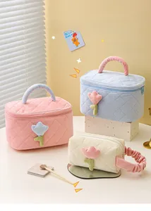 Three corduroy cosmetic bags in pink, blue, and cream with tulip floral patterns