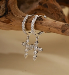 Macro shot of S925 silver cross earrings with full diamonds on a rustic wood branch