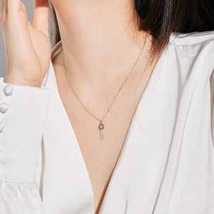 Close-up of S925 silver key necklace with blue devil eye crystals worn by a model