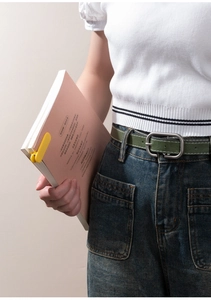Detail of dark green leather belt with matte silver buckle worn on casual denim jeans