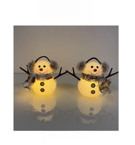 Macro view of glowing Christmas snowman lamps with plaid scarves and warm LED light