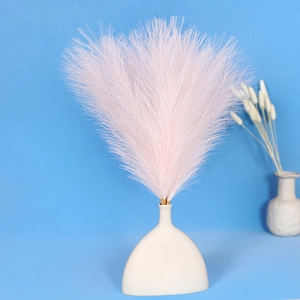 Pink artificial pampas grass bouquet in a white ceramic vase with blue background