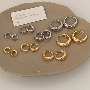 Minimalist gold and silver chunky hoop earrings in various sizes on a ceramic tray