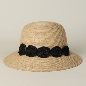 Close-up of elegant raffia sun hat featuring a black crocheted rose flower band detail