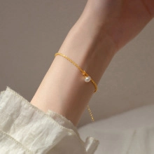Detailed view of minimalist gold chain bracelet featuring a single freshwater pearl bead