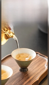 Macro view of kiln-altered ceramic tea cup showing natural green glaze and pouring tea