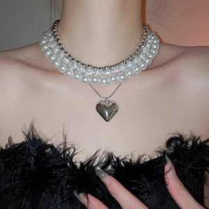 Détail macro d'un collier multicouche avec perles et grand pendentif en forme de cœur