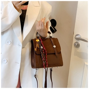 Detalle de bolso bandolera vintage marrón oscuro con pañuelo de seda y amuleto de llave