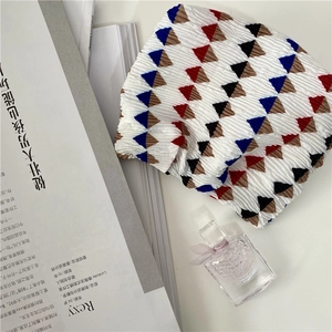 Detail of pleated chiffon fabric with colorful geometric triangle pattern on white base