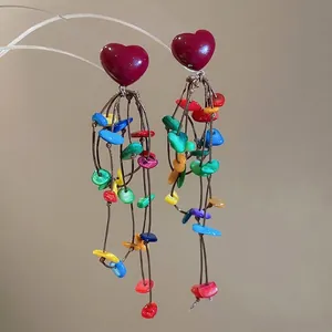 Bohemian long tassel earrings with red heart and colorful shell pendants on a stand