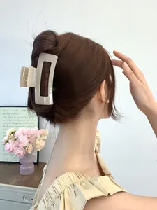 Detail of a beige hollow rectangular hair claw clip worn on a thick hairstyle