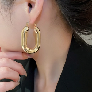 Primo piano di orecchini a cerchio ovali dorati a forma di U per un look di lusso
