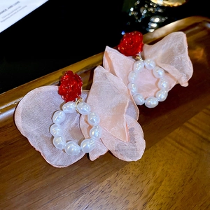 Macro detail of floral pearl earrings with pink organza petals and silver needles