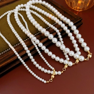 Close-up of vintage pearl necklaces with gold magnetic clasps on a dark wood base