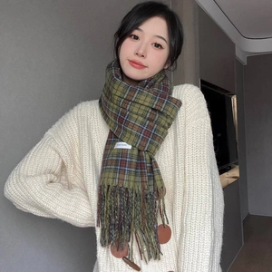 Detail of green and brown plaid scarf featuring soft cashmere-like fringe on a model