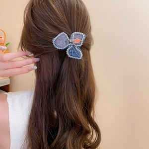 Detail of blue petal hair clip with pearls and sequins on brown wavy hair