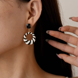Detailed view of vintage gold earrings with black and white spiral enamel on model
