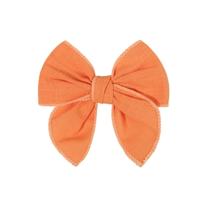 Detailed view of the orange fabric texture and fine stitching on the bow hair clip