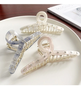 Three acetate shark clips in white, blue and pink with rhinestones on a white plate