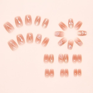 Gros plan d'ongles dégradés rose nude avec lignes dorées, perles et nacre