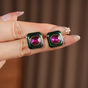 Detail of vintage square emerald green enamel earrings with pink gemstone in gold frame