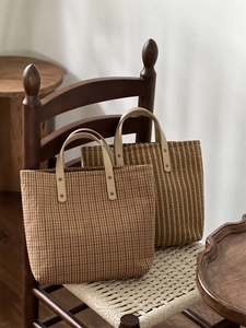 Close-up of vintage plaid canvas tote bag with leather handles and metal rivet detail