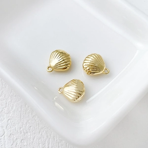 Three 14k gold-plated shell pendants displayed on a white textured ceramic tray