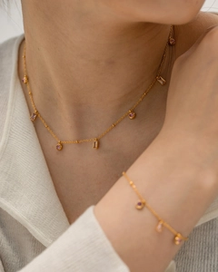 Détail de l'ensemble collier et bracelet doré avec pierres roses rondes et rectangulaires