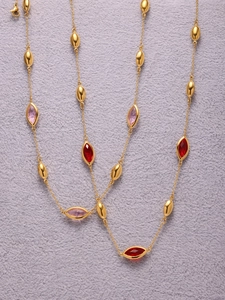 Detail of 18k gold-plated necklace featuring marquise-cut red and pink glass stones